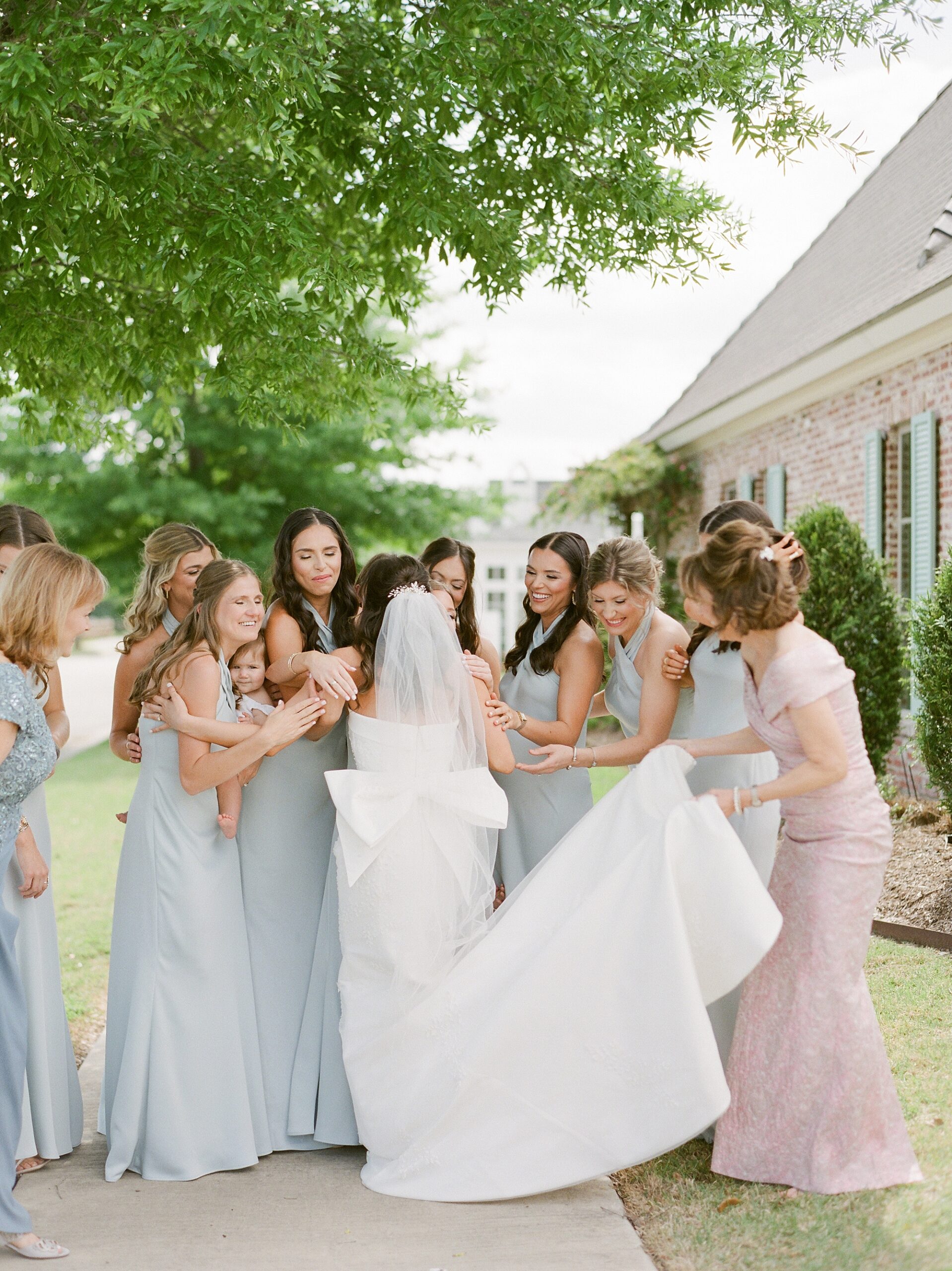 bridesmaids and mother help bride walk outside for first look