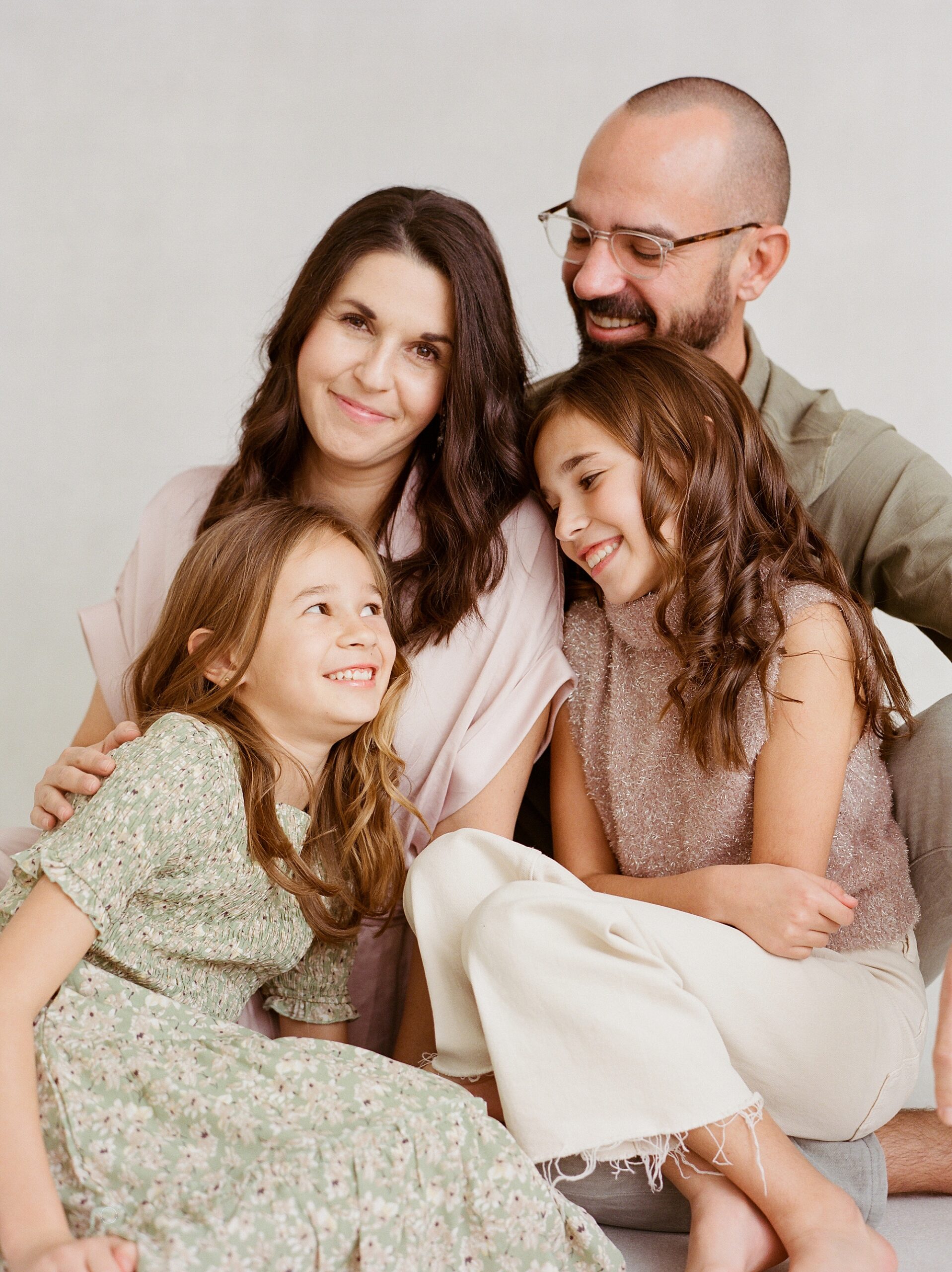 family of four snuggles close together laughing during studio family photos