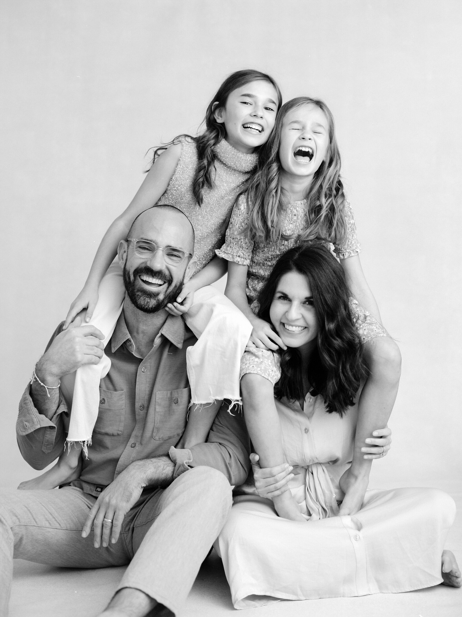 family of four laughs together during family photos in Lafayette LA