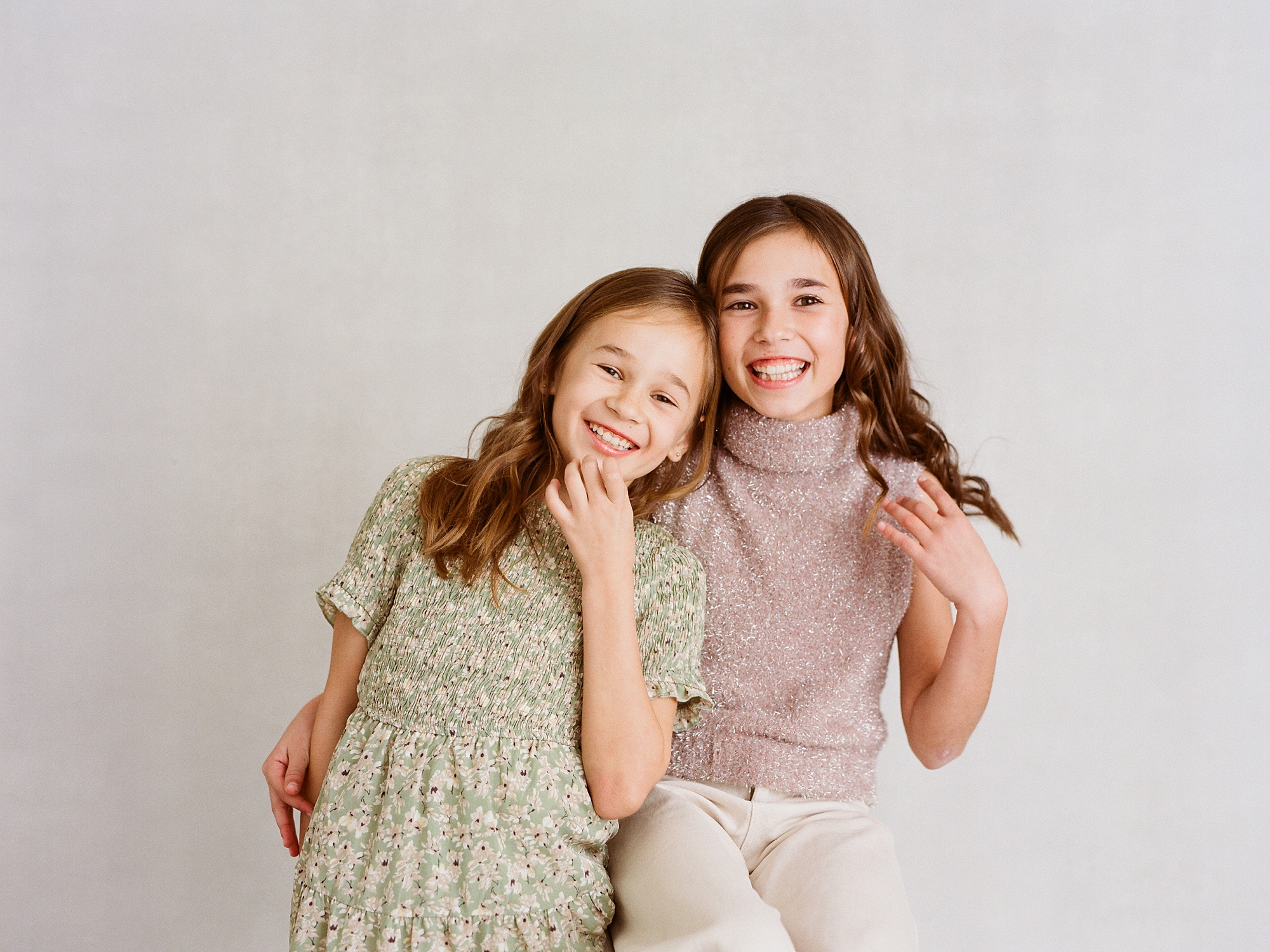 sisters hug in front of studio backdrop during family photos in Lafayette LA