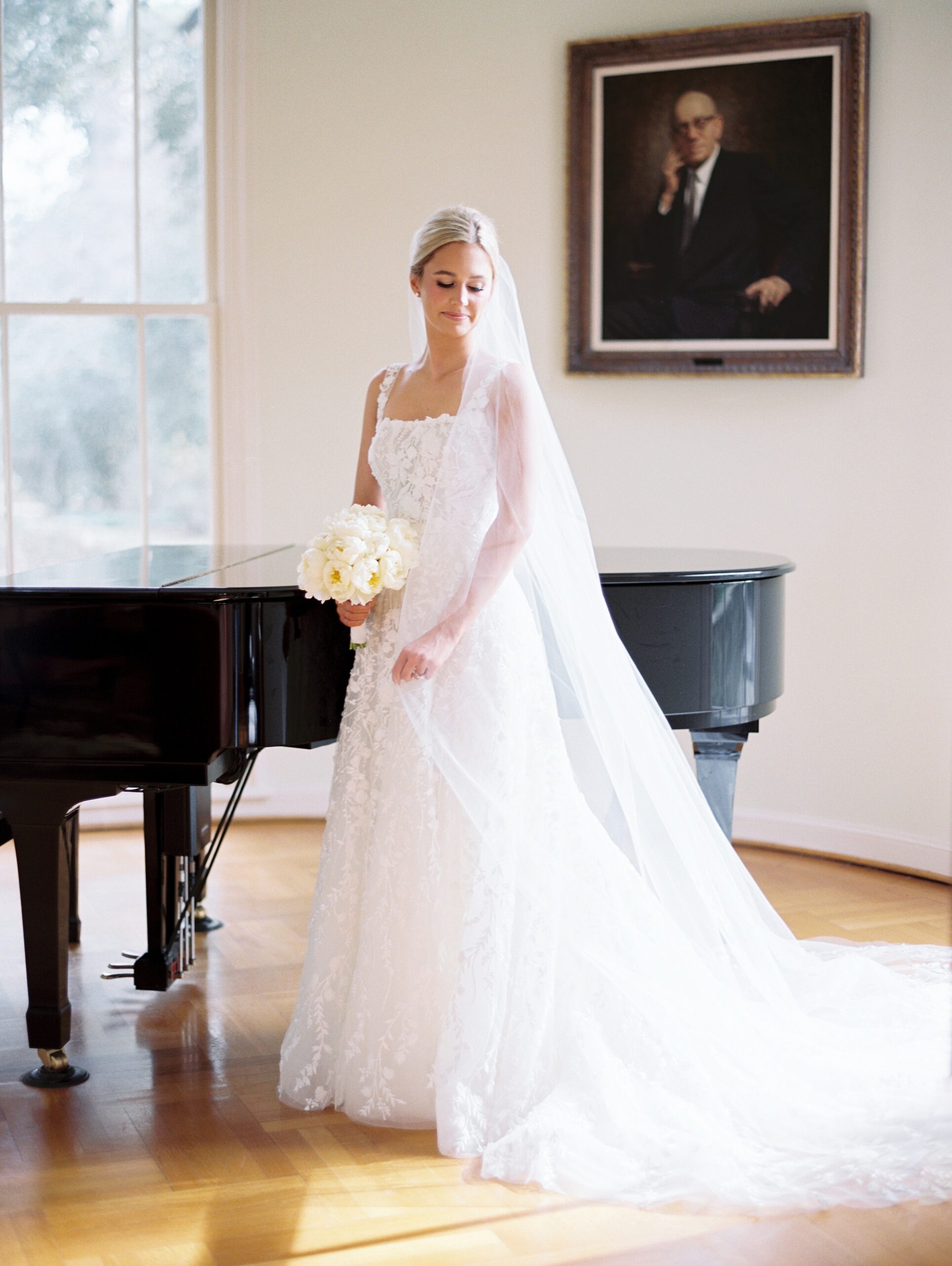 blonde bride poses leaning against grand piano at the UL Alumni Center
