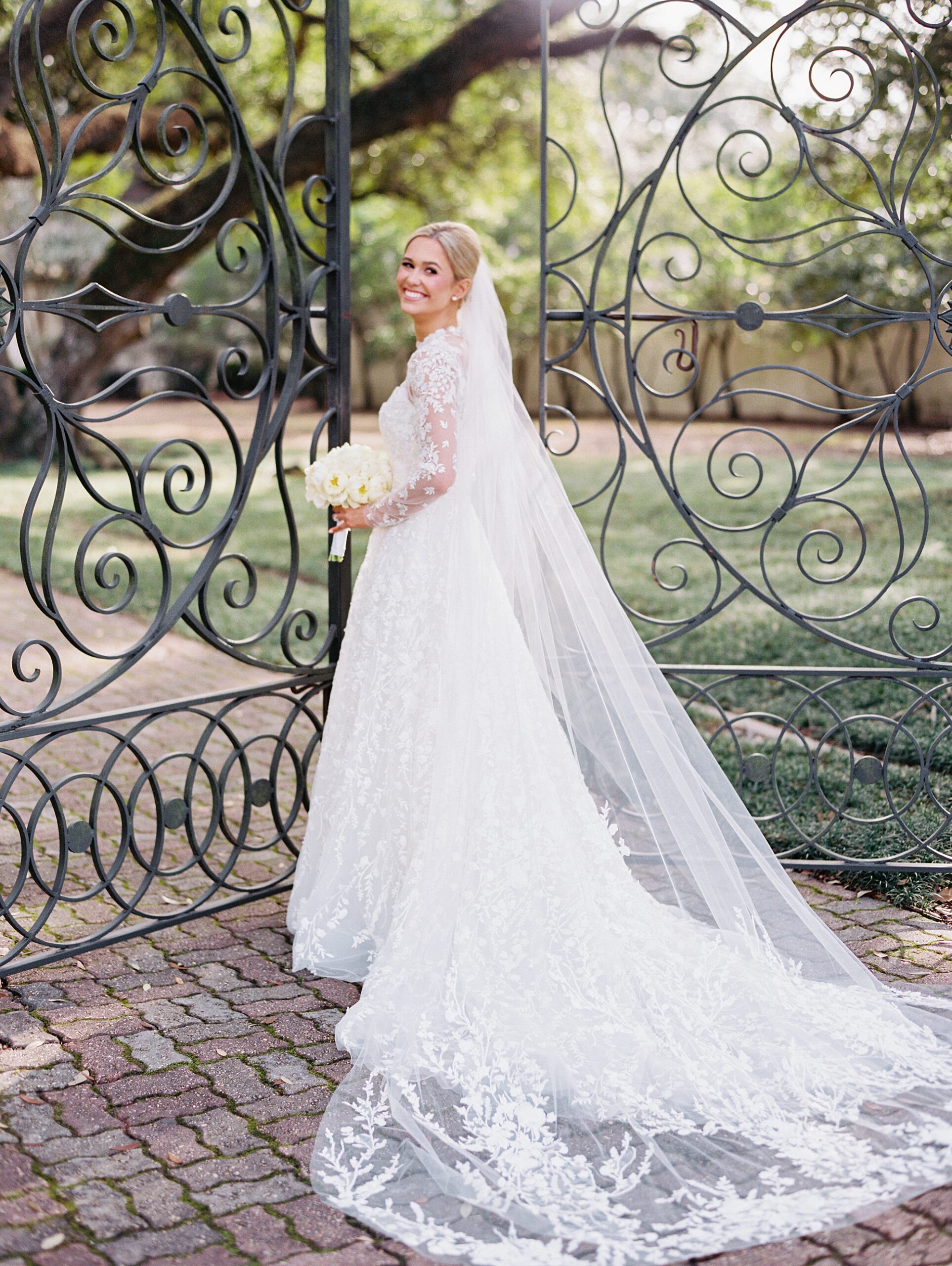 bride walks towards wrought iron gate during UL Alumni Center bridal portraits