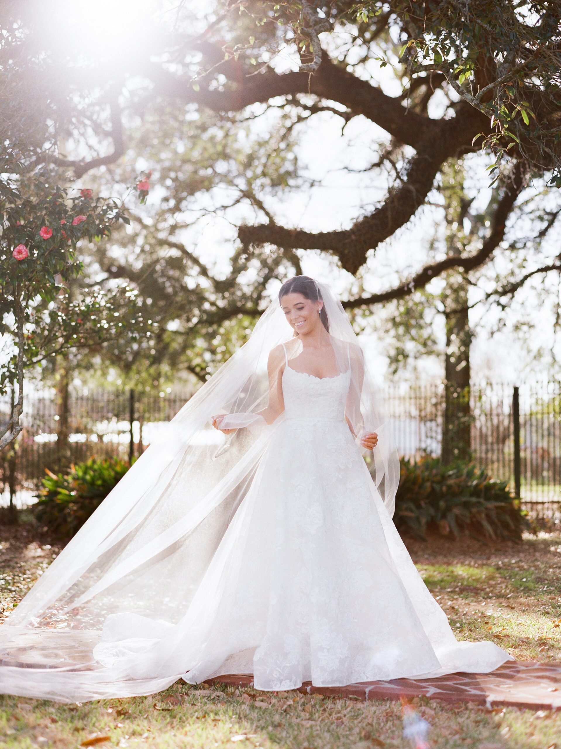 bride holds out veil standing in wedding dress during John Nickerson House bridal portraits 