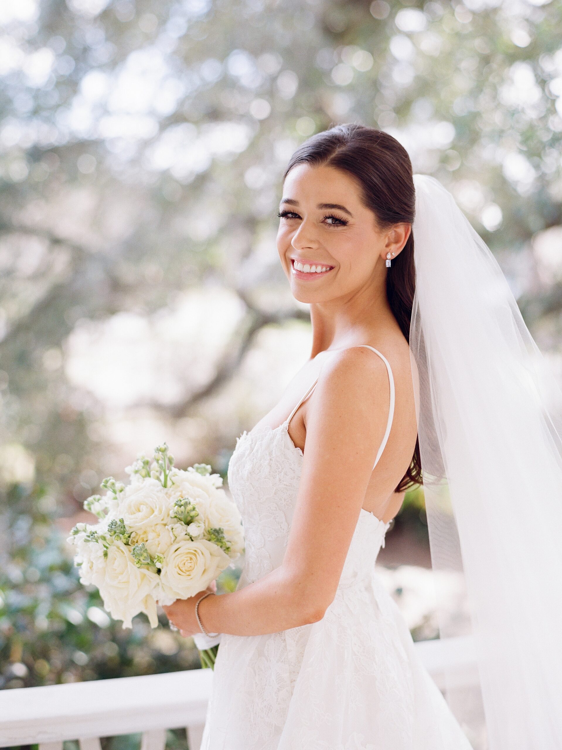 bride smiles over her shoulder with ivory rose bouquet 