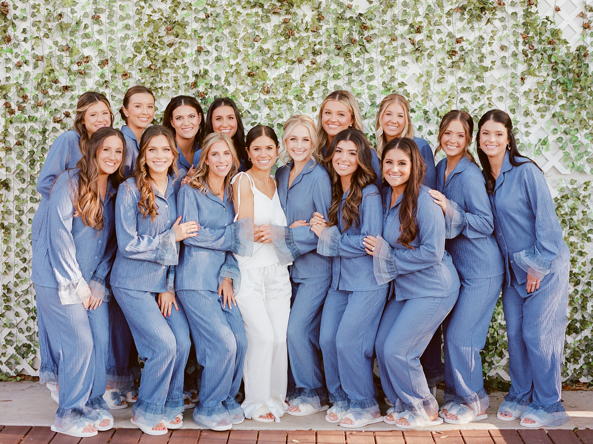 bride poses with bridesmaids in blue pajamas on wedding morning 