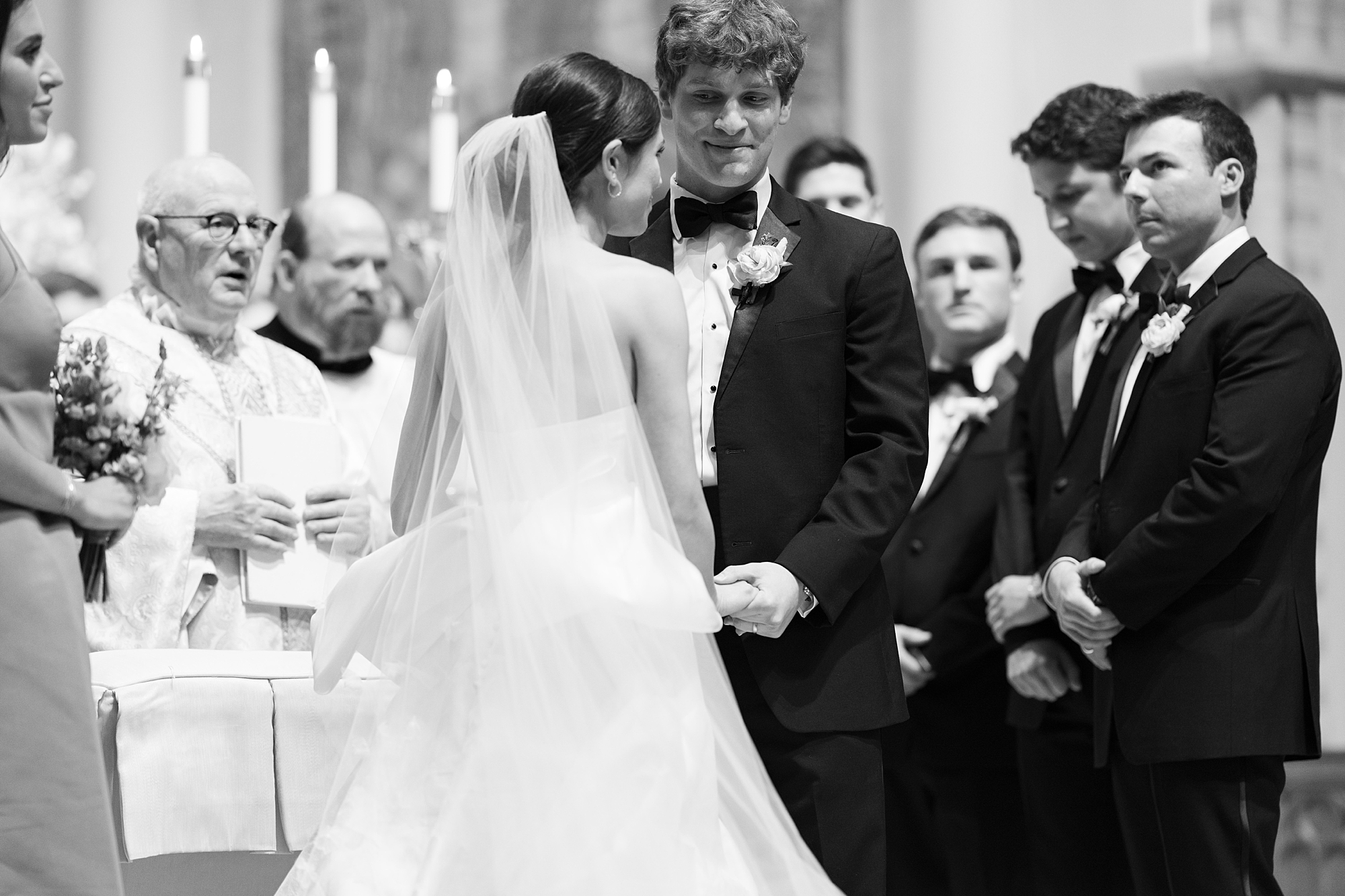 bride and groom hold hands during wedding ceremony at St. John Cathedral