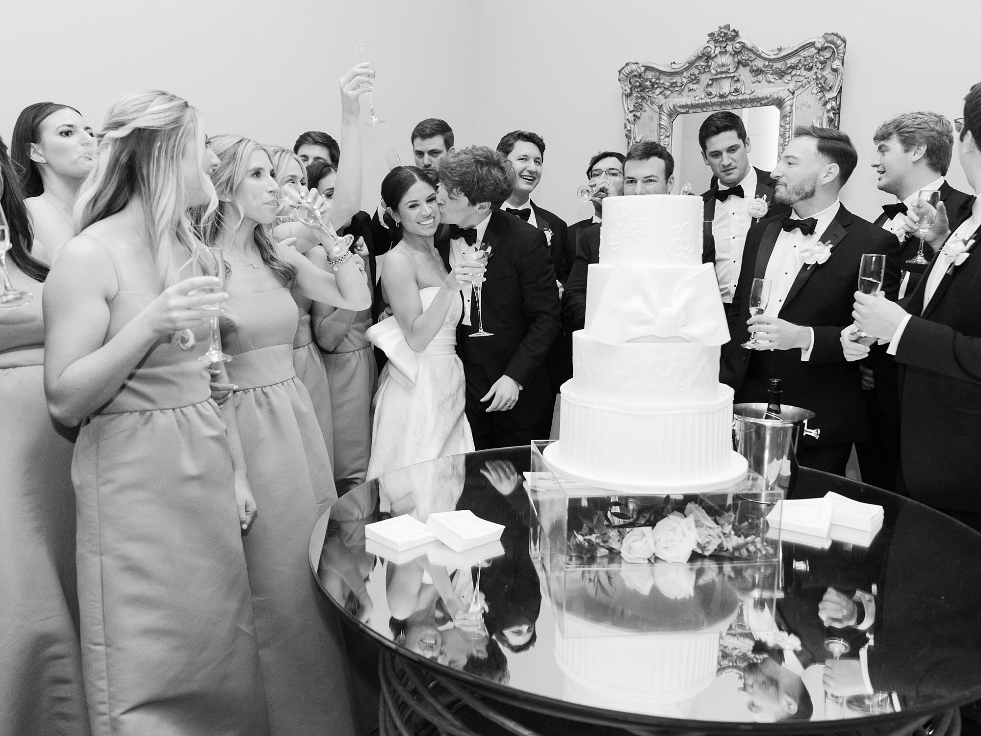 bride and groom hug near cake while wedding party cheers 