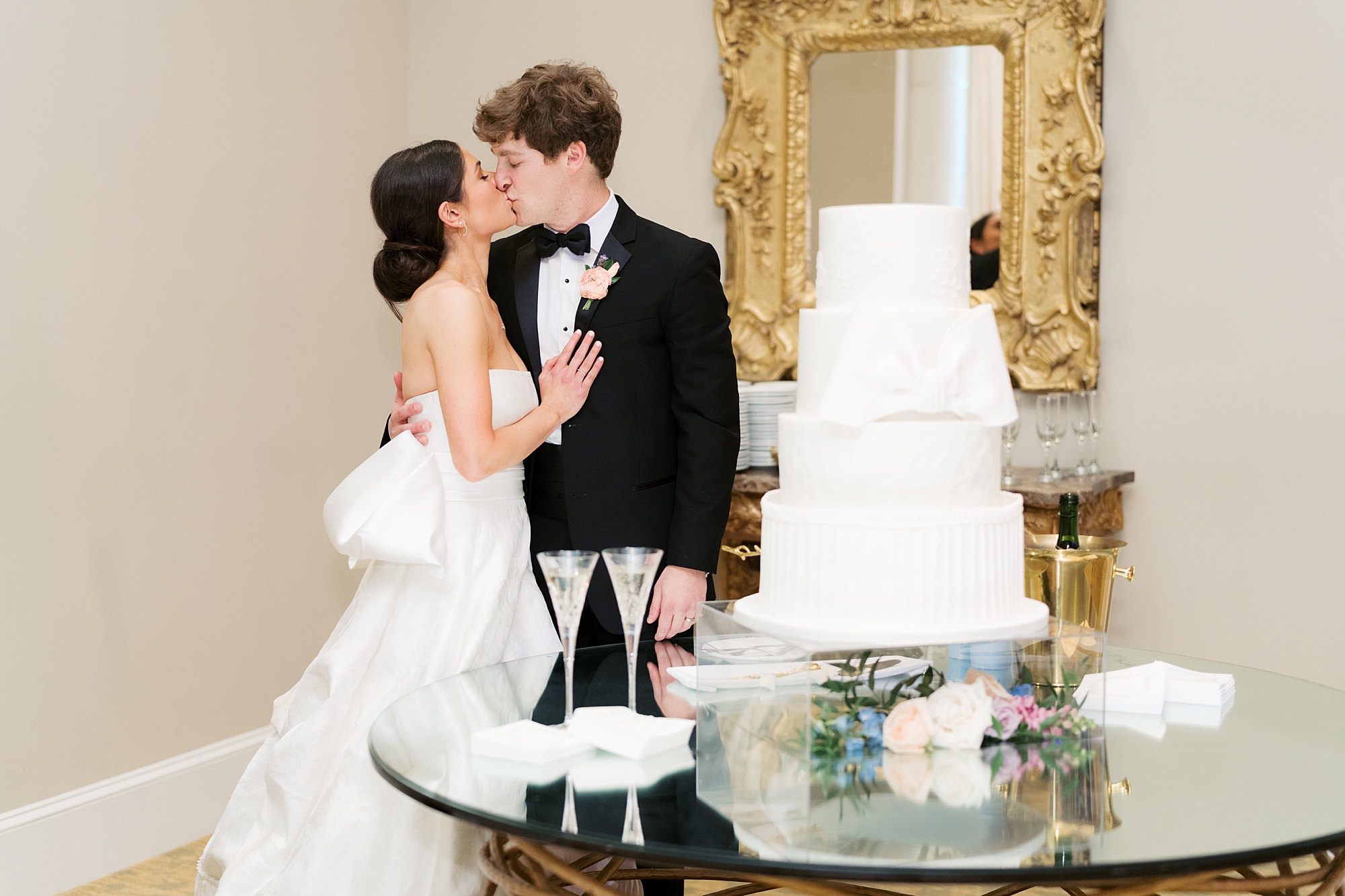 newlyweds kiss by tiered wedding cake during Le Pavilion wedding reception in Lafayette LA