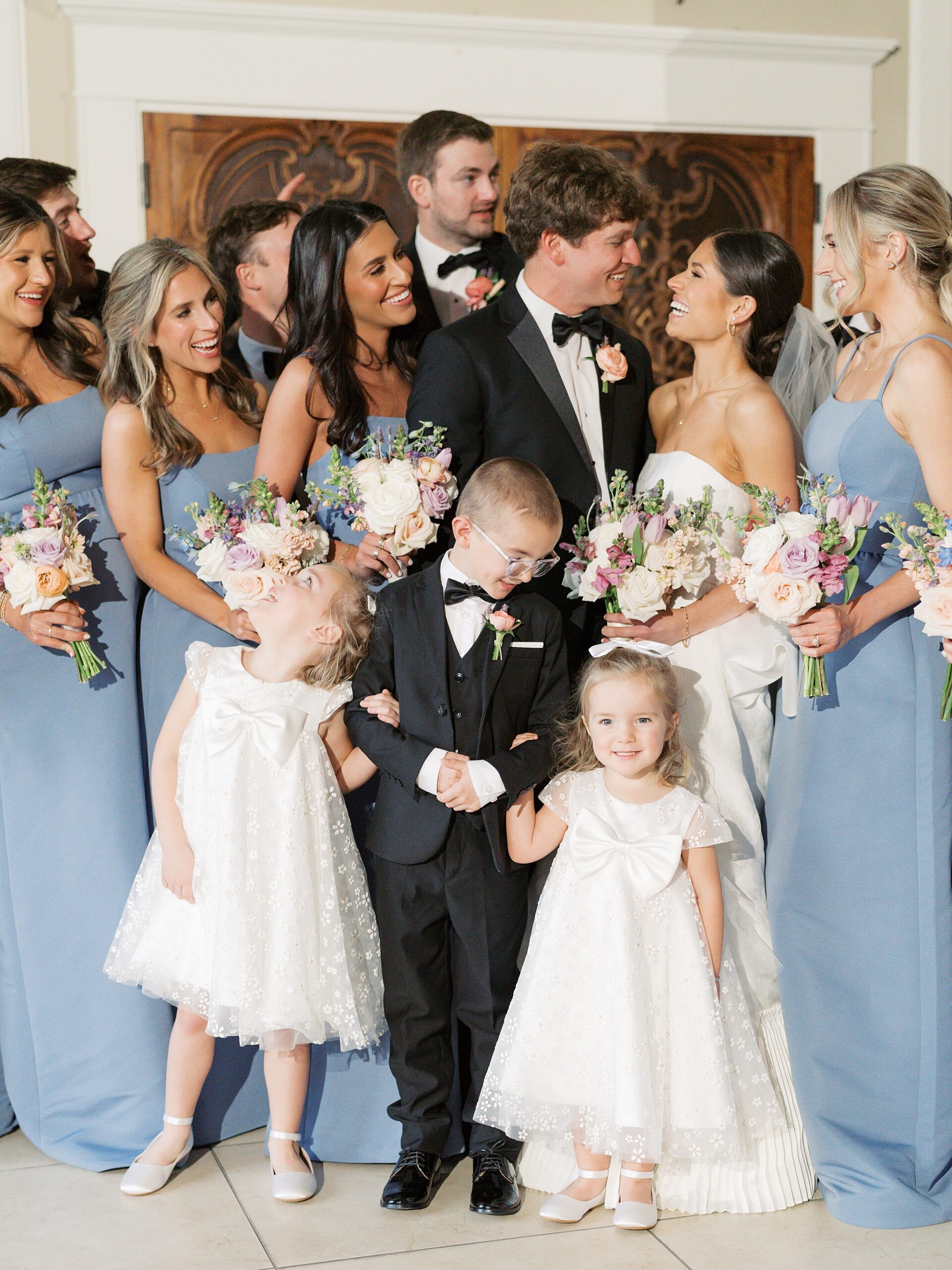 newlyweds smile with bridesmaids in blue around them 